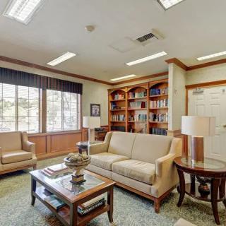 A cozy living room with sofas, chairs, and bookshelves.