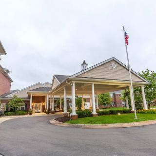 A building entrance with a covered driveway and a flagpole nearby.