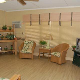 A cozy living room with wicker chairs, a television, and potted plants.