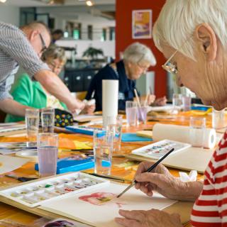 A group of elderly individuals engaging in a watercolor painting class.