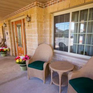 A cozy porch with wicker chairs and a table, adorned with colorful flower pots.