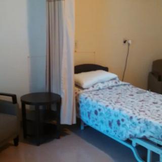 A hospital room featuring a bed with floral sheets and a privacy curtain.