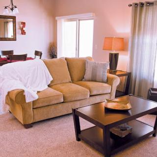 A cozy living room featuring a beige sofa, a wooden coffee table, and warm lighting.