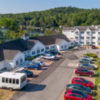 Aerial view of a hotel with a parking lot surrounded by lush greenery.