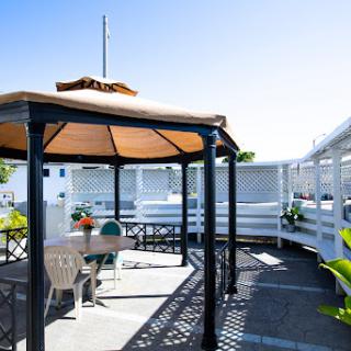 A cozy outdoor gazebo with seating, perfect for relaxation on a sunny day.