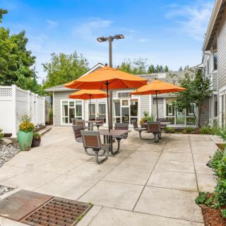 A sunny patio with orange umbrellas and outdoor seating.