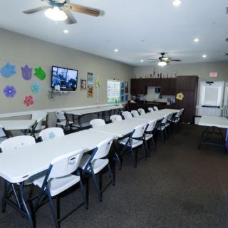 A spacious conference room with long tables and chairs, ideal for meetings and presentations, featuring ceiling fans and colorful wall decorations.