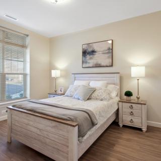 A modern bedroom with a neatly made bed, nightstands, and soft lighting.