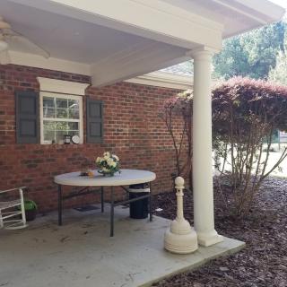 A cozy outdoor patio with a table and flower arrangement.