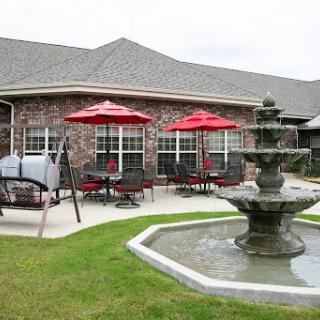 A serene outdoor dining area featuring a beautiful fountain and vibrant red umbrellas.