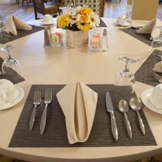 An elegantly set dining table with neatly arranged silverware, a folded napkin, and a floral centerpiece.