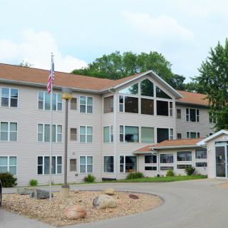 A residential apartment building with a flagpole and surrounding greenery.