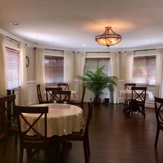 A cozy dining room with round tables, wooden chairs, and soft lighting.