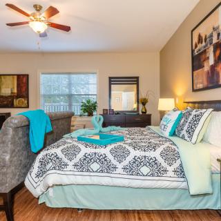 A well-decorated bedroom with a neatly made bed, featuring patterned bedding and vibrant accents.