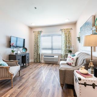 A cozy living room with modern decor, featuring comfortable seating, a television, and a large window with curtains.