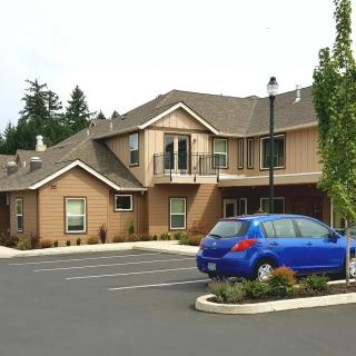 A residential building with a blue car parked in the driveway.