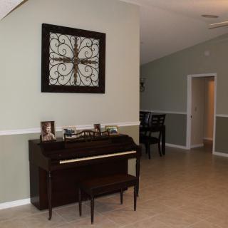 A living room with a piano and decorative wall art.