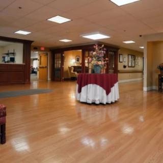 A spacious lobby with wooden flooring, decorated tables, and comfortable seating.