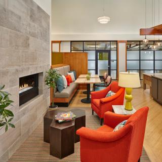 A modern and inviting living room featuring stylish orange chairs, a cozy fireplace, and contemporary furnishings.