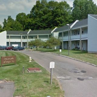 A view of an apartment complex with a parking lot surrounded by trees.