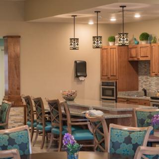 A modern kitchen and dining area featuring wooden cabinetry, pendant lighting, and comfortable seating.