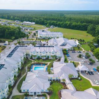 Aerial view of a residential complex with a pool and surrounding greenery.