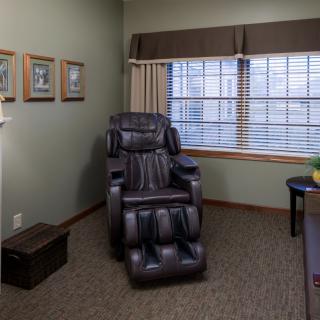 A cozy room featuring a massage chair by the window for relaxation.