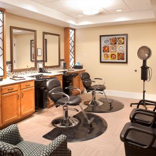 An elegant beauty salon interior with styling chairs, mirrors, and a hair dryer.