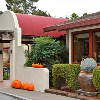 An inviting restaurant entrance decorated with pumpkins and greenery, showcasing a cozy autumn ambiance.