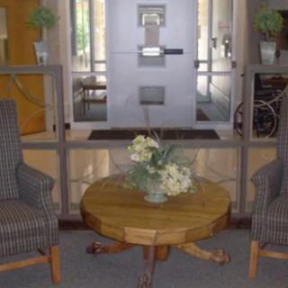 A cozy lobby setup featuring two striped chairs and a wooden table with a floral centerpiece.