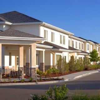A row of modern townhouses in a suburban area under a clear blue sky.