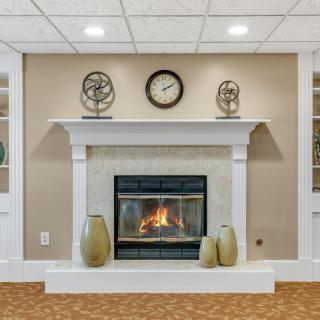 A cozy living room with a stylish fireplace, decorated with a clock and ornaments on the mantel.