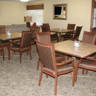 A dining area with several tables and chairs arranged neatly on a carpeted floor.
