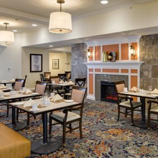 A cozy dining area with neatly arranged tables and chairs, featuring warm lighting and elegant decor.