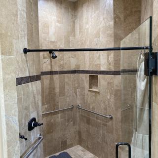 A modern shower with a glass door and tiled walls.