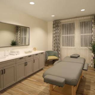 A serene massage room featuring a comfortable massage bed, modern cabinetry, and soft lighting.