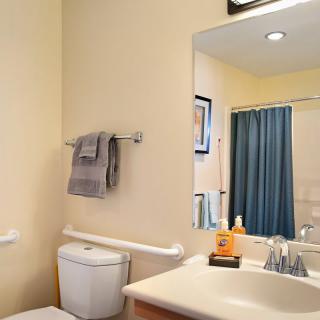 A clean and well-organized bathroom with a mirror, sink, and blue shower curtain.