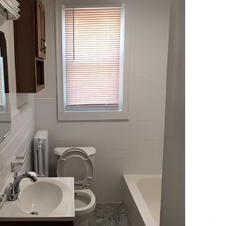 A small bathroom featuring a sink, toilet, and bathtub with a window covered by blinds.
