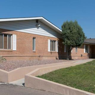 A brick residential house with a green front yard and clear blue sky.