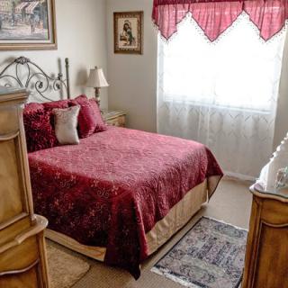 A cozy bedroom with classic wooden furniture and a richly colored bedspread.