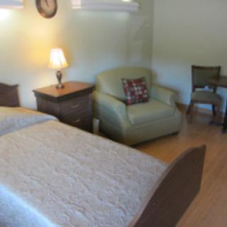 A cozy bedroom featuring a comfortable bed, an inviting armchair, and warm lighting.