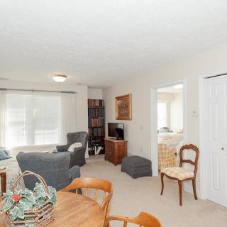 A cozy living room with armchairs, a dining table, and a television set.