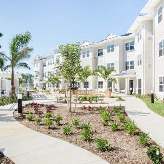 A modern apartment complex with landscaped walkways and palm trees.