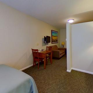 A cozy hotel room with a bed, desk area, and seating space.