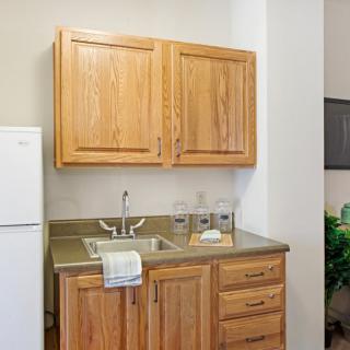 A small kitchen area featuring wooden cabinets, a sink, and a refrigerator.