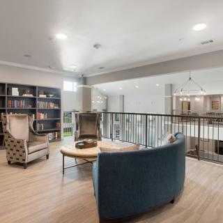 A cozy living room with modern furniture and a bookshelf, providing a comfortable seating area.