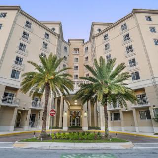 A modern apartment building with palm trees in front, showcasing urban architecture.