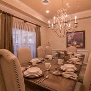 An elegantly set dining room table with a chandelier overhead.