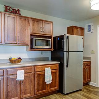 A modern kitchen featuring wooden cabinets, a stainless steel refrigerator, and a microwave.