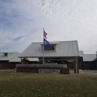 A government building displaying the American flag and another flag against a cloudy sky.